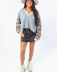 Boho-inspired Everyday Ease Denim Patchwork Top featuring mixed fabrics and relaxed fit, paired with black denim skirt and ankle boots.