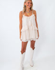 ivory romper styled for a summer country concert with bandana charm necklace and boots
