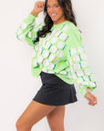 Side view of Queen of Sparkles Green Golf Ball & Tee Sweatshirt with relaxed fit and vibrant sequin golf design, paired with black skirt.