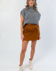Stylish Amber Chai Sienna Twill Bow-Detail Mini Skirt paired with a gray knit top and cream boots, perfect for a chic autumn look.