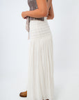 Person wearing a long white skirt on a plain background