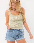 Beach Green Striped Tank Top: Your Summer Essential with scoop neckline and 'BEACH' text, paired with denim shorts for a casual beach look.