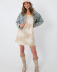 Fashion model in beige floral dress, denim jacket, and beige cowboy boots