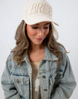 Model wearing Bride Embroidered Trucker Hat with denim jacket and floral dress for bridal accessories