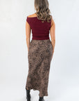 Back view of Friday Feeling Burgundy Asymmetrical Top highlighting fitted silhouette, paired with a flowy leopard print skirt.