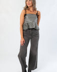 Full front view of Girly Girl Shiny Black Gingham Peplum Top paired with high-waisted gray jeans and black boots for a trendy look.