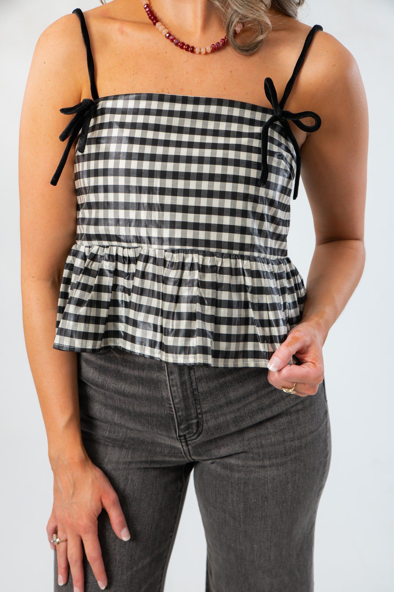 Close-up of Girly Girl Shiny Black Gingham Peplum Top featuring velvet bow details and a flattering cropped peplum hem.