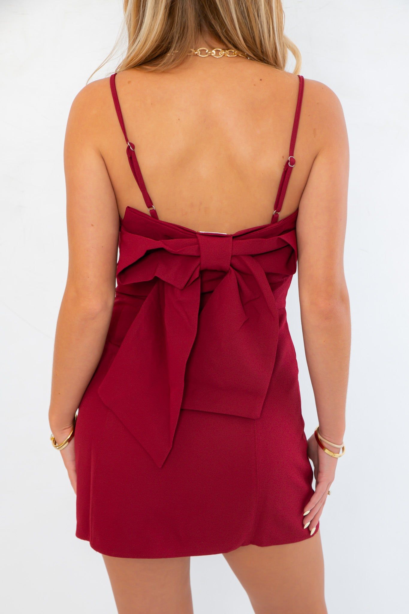 Back view of Jodie Burgundy Dress featuring a large statement bow and adjustable spaghetti straps for a custom fit.