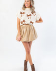 Cute cropped Football Bow Mock Neck Cream Sweater paired with tan bubble skirt and brown ankle boots, perfect for stylish gameday outfits.