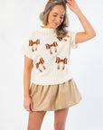 Model wearing Football Bow Mock Neck Cream Sweater with brown bow accents and short sleeves, styled for a cute and sporty gameday look.