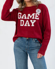 Close-up of Game Day Garnet Knit Sweater showing textured knit fabric, white GAME DAY lettering, and cozy oversized design.