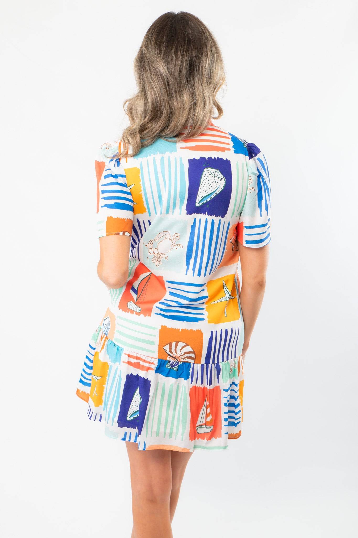 Back view of THML At Sea Nautical Printed Dress showing tiered hem and vibrant seaside illustrations ideal for beach or resort outings.