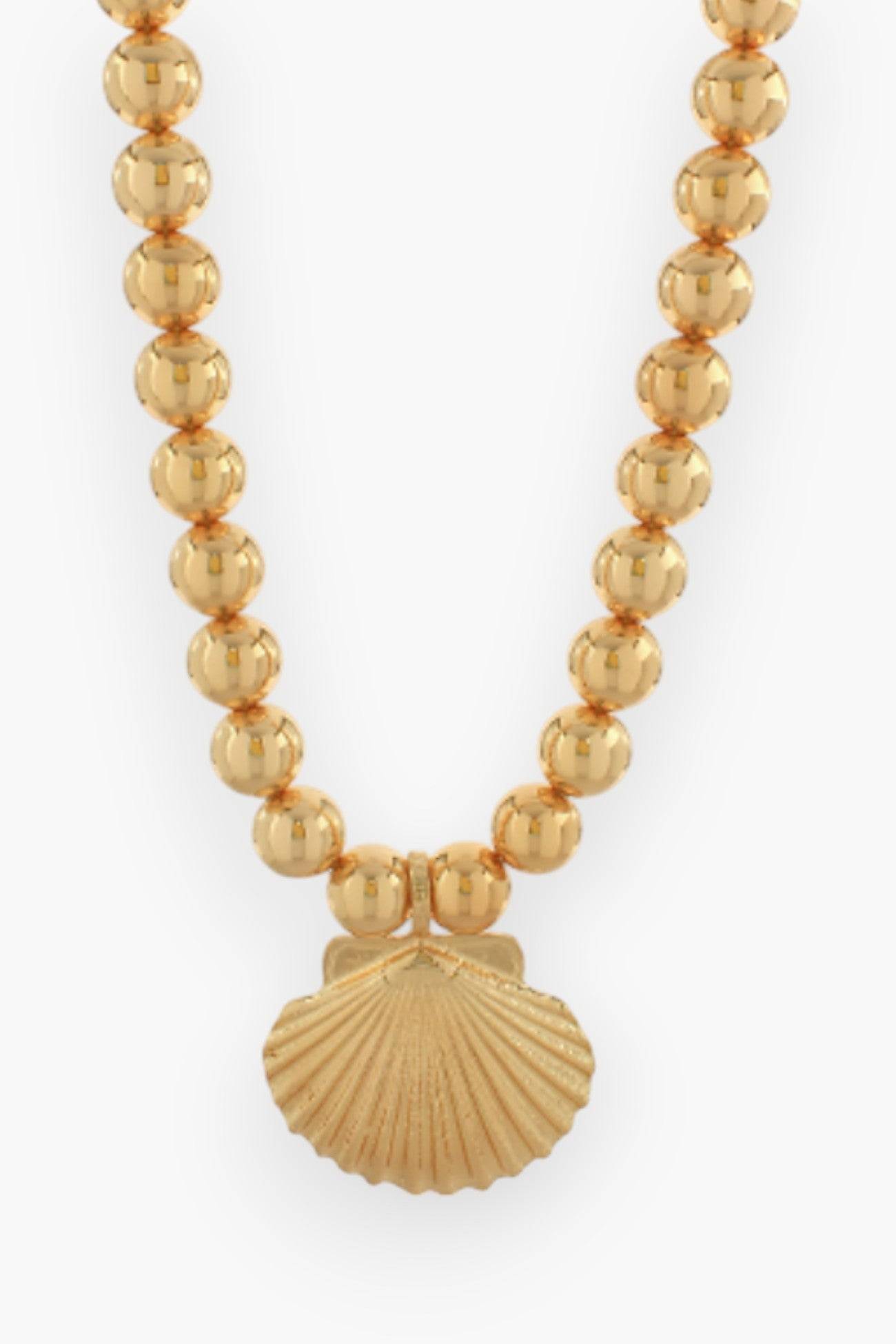 Gold Statement Shell Necklace featuring a bold gold shell pendant on a beaded chain. A luxe beach wear accessory perfect for summer and vacation outfits.