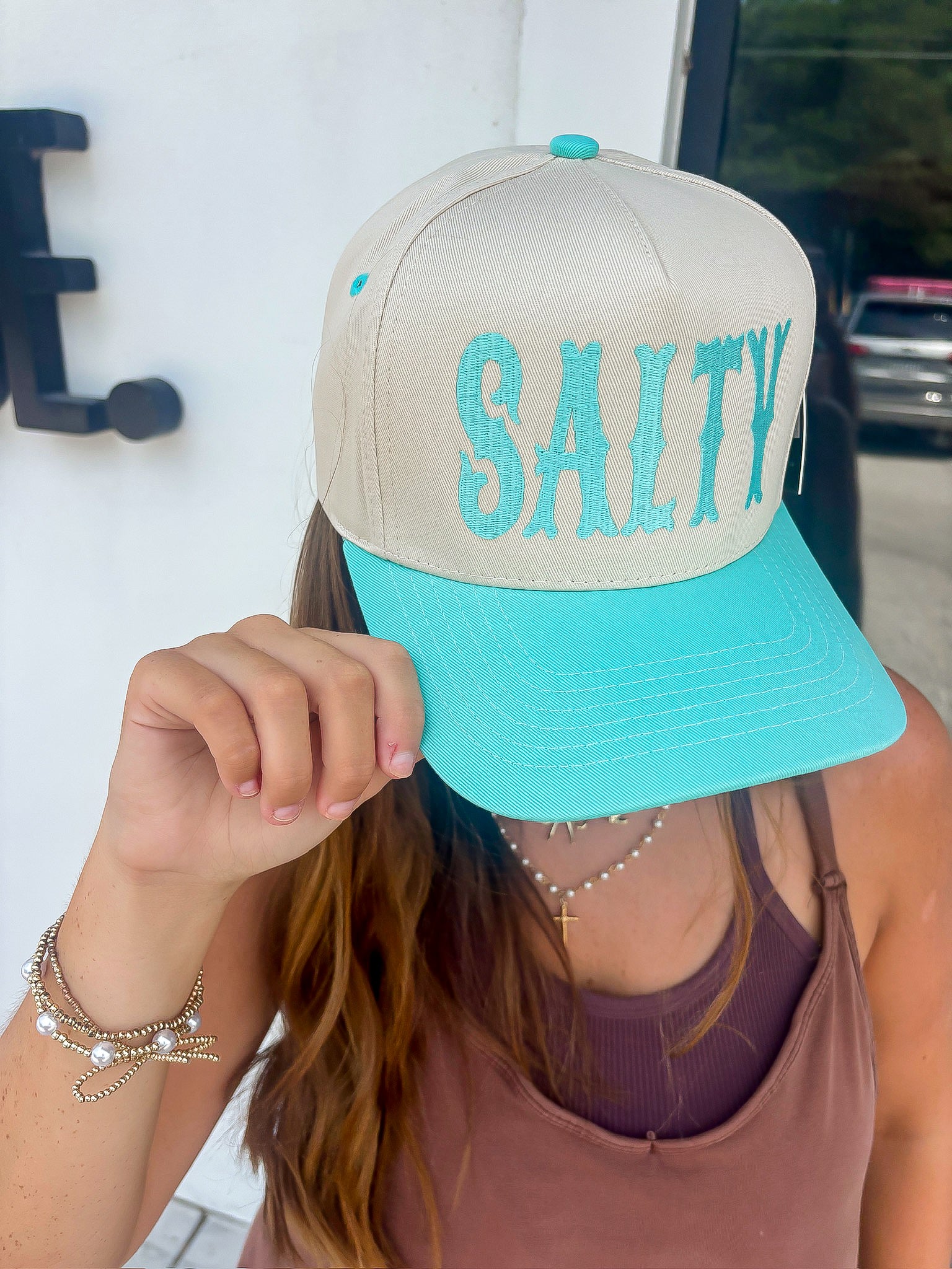 Person wearing a beige and turquoise cap with 'SALTY' text.