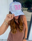 Trendy You Look Like You Love Me Camo Trucker Hat styled with casual outfit, showcasing pink embroidered lyrics and western-inspired design.
