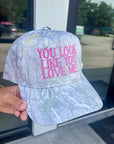 Close-up of You Look Like You Love Me Camo Trucker Hat with bold pink lyrics embroidery, adjustable snapback, and durable camo canvas.
