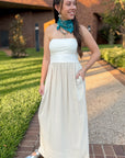 Oatmeal linen dress strapless and flowy, styled outdoors with silver flats and turquoise bandana for a casual summer look.