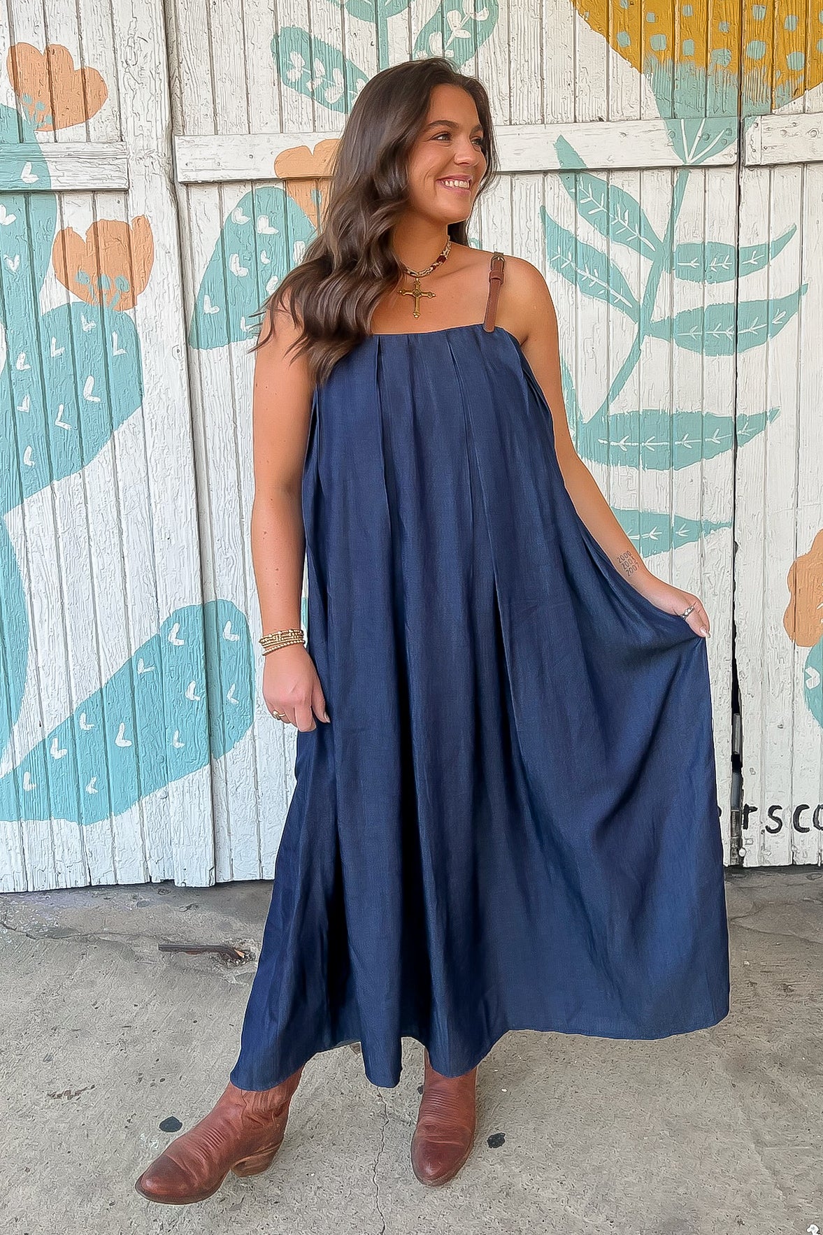 THML Denim Buckle Strap Midi Dress with flowy silhouette and brown buckle straps, styled with ankle boots for a casual fall look.
