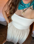 Close-up of strapless oatmeal linen dress with gathered waist, accessorized with layered necklaces and turquoise bandana scarf.