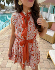 Close-up of Paloma Please Scallop Appliqué Sleeveless Dress showing floral appliqué, scalloped neckline, and belted waist in rust orange.
