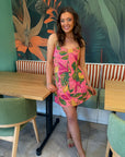 Cabana Nights Tropical Printed Mini Dress in coral pink with green and yellow leaf pattern, styled for a casual summer outing.