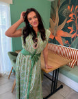 Printed satin midi dress in emerald with a flattering waist tie and vintage-inspired pattern, ideal for summer events.
