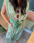Emerald Deco Printed Satin Midi Dress with Art Deco pattern, green sash belt, and front buttons, styled for a chic daytime look.