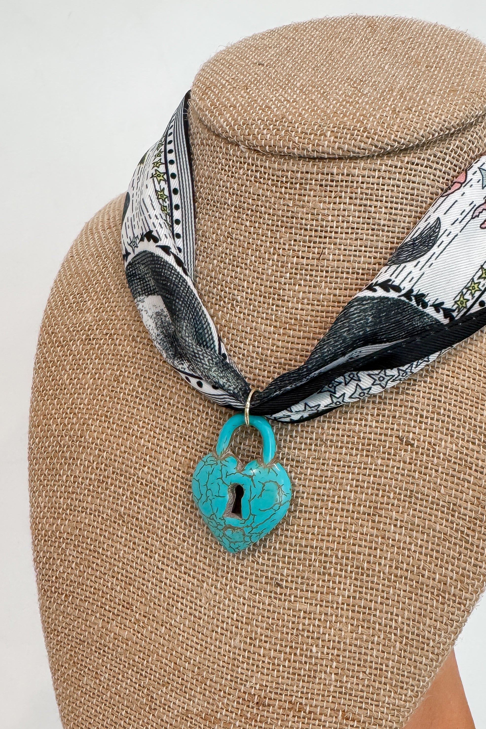 Close-up of Moon Phase Necklace featuring heart-shaped turquoise lock charm on celestial print bandana, perfect for fall fashion accessories.