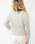 Back view of Liza Mint Cable Knit Cardigan highlighting its textured cable knit design and relaxed silhouette. A cozy and stylish wardrobe essential.