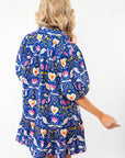 Back view of the Morgan Folk Love Mini Dress showcasing its relaxed fit, folk-inspired print, and stylish ruffle hem for a charming look.