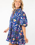 Side view of the Morgan Folk Love Mini Dress highlighting its flowy fit, vibrant print, and playful ruffle hem for a chic casual style.
