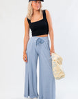 Free People Soft Chambray Wide-Leg Lounge Pants in light blue with high-rise fit, drawstring waist, and side pockets styled with a black crop top.