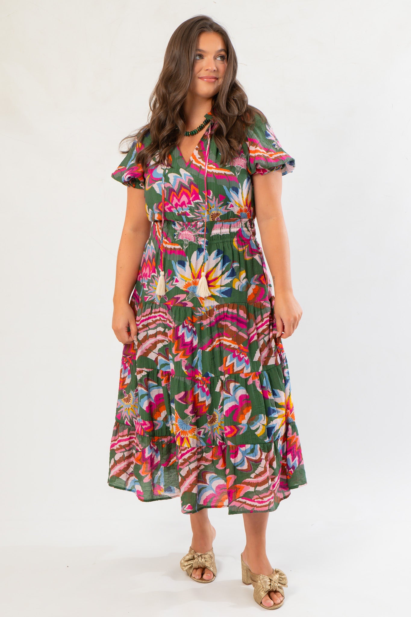 Front view of THML Printed Puff Sleeve Tiered Maxi Dress showcasing its green floral design, smocked waist, and tassel tie neckline.