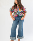 Model wearing THML Printed Puff Sleeve V-Neck Top with hands in pockets, emphasizing the blouse's bold floral print and casual-chic appeal.