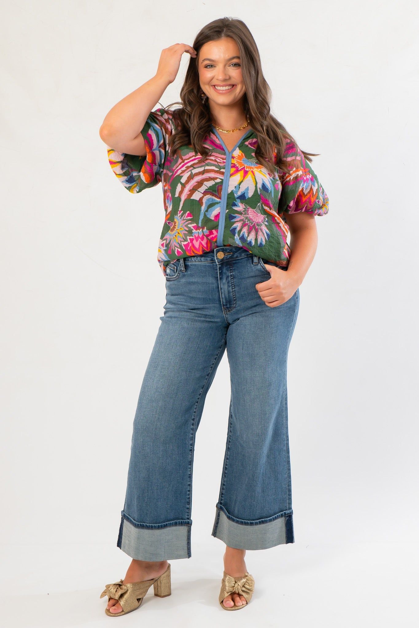 Front view of THML Printed Puff Sleeve V-Neck Top – Green Floral Print Blouse styled with denim pants, highlighting its colorful design and flattering cut.