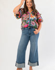 Front view of THML Printed Puff Sleeve V-Neck Top – Green Floral Print Blouse styled with denim pants, highlighting its colorful design and flattering cut.