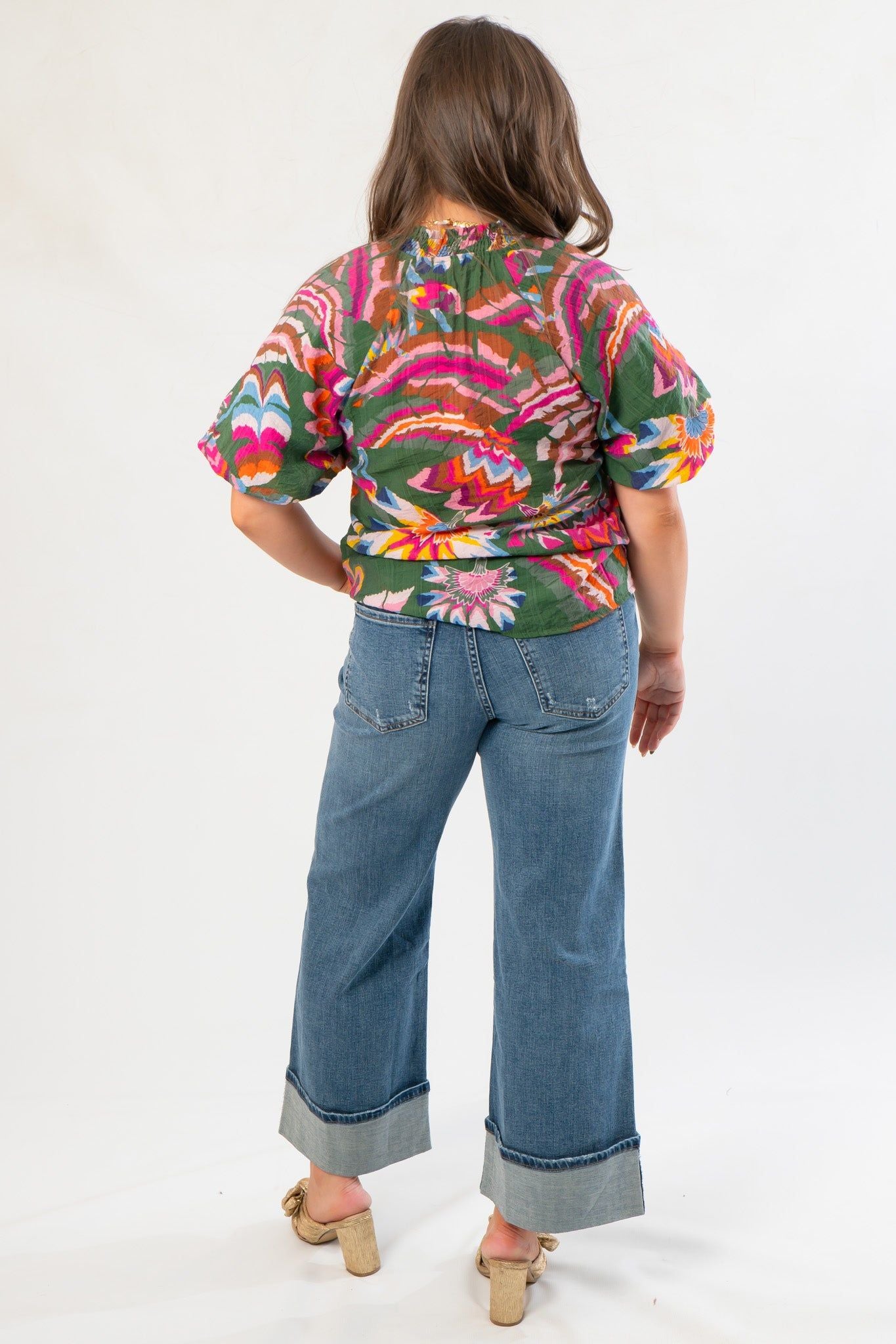 Back view of THML Printed Puff Sleeve V-Neck Top showing gathered detail and vibrant floral pattern, styled with cuffed denim jeans for a trendy look.