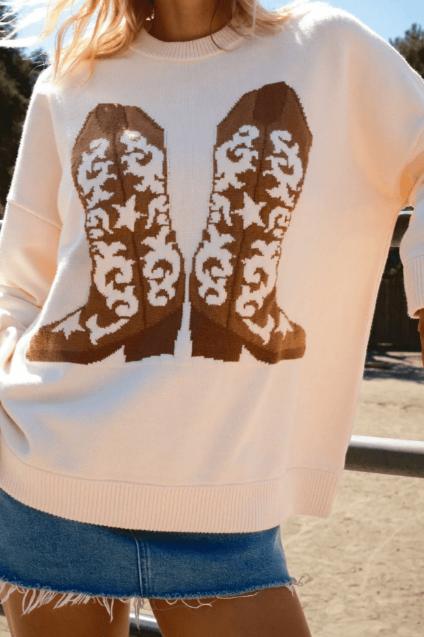 Show Me Your Mumu Cowboy Boot Knit Stay Awhile Sweater in cream with brown western boot graphic, styled with a denim mini skirt for a cozy fall look.