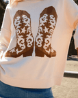 Show Me Your Mumu Cowboy Boot Knit Stay Awhile Sweater in cream with brown western boot graphic, styled with a denim mini skirt for a cozy fall look.