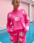 Vibrant hot pink shell knit sweater by Show Me Your Mumu, styled with matching shorts for a chic resort-ready look. Ideal for spring break or beachside lounging.