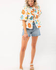 Model posing in a Spring Floral Tie-Front Top with a playful floral print, puff sleeves, and a relaxed fit, perfect for spring and summer styling.