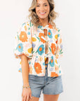 Spring Floral Tie-Front Top with bright floral prints, puff sleeves, and a peplum hem, styled with denim shorts for a fresh spring look.