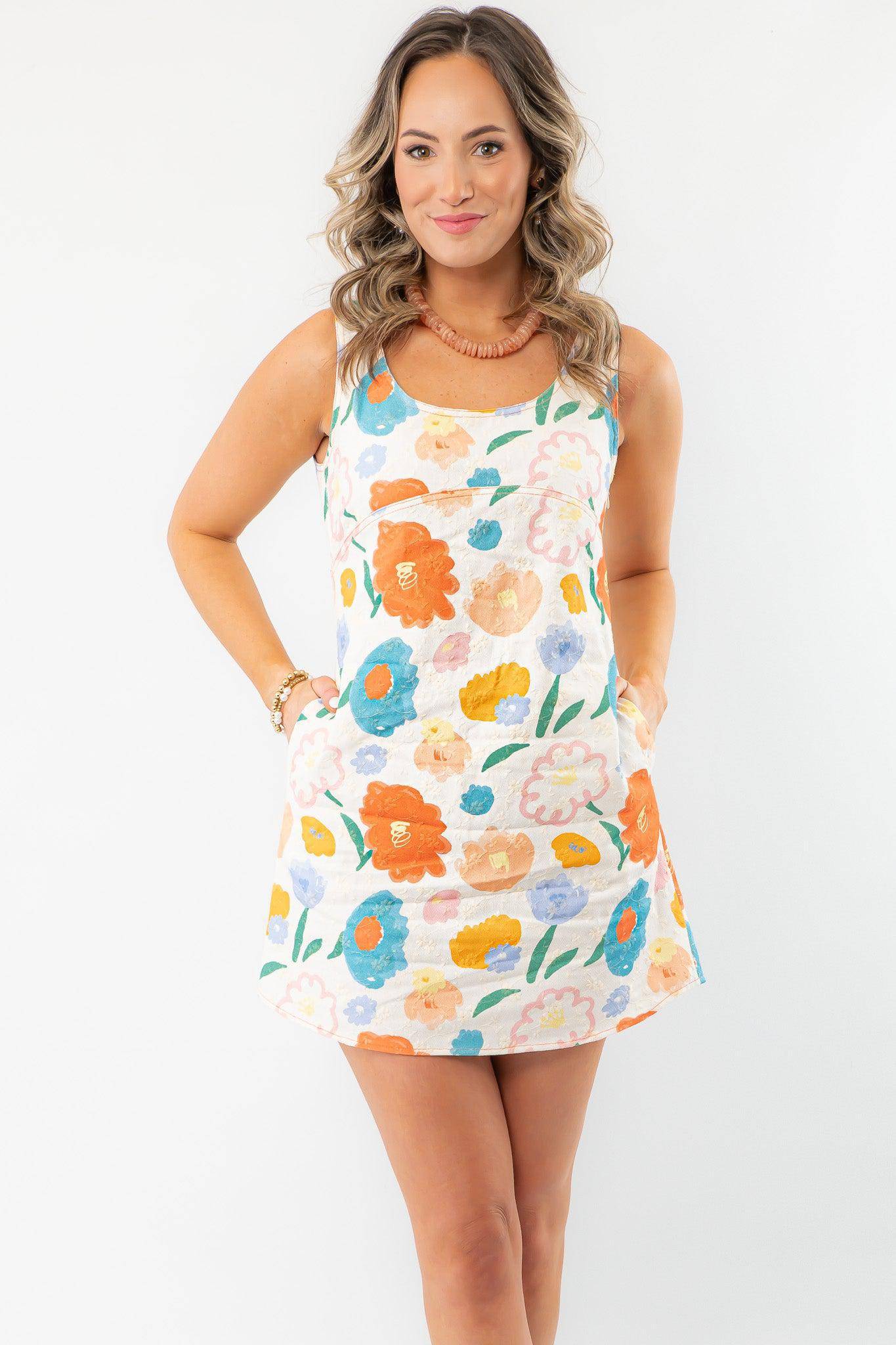 Model wearing the Spring Multi-Floral Mini Dress with pockets, a scoop neckline, and a colorful floral design, ideal for warm-weather styling.
