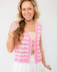 Model wearing the Sweet As Can Be Pink Crochet Open Front Tie Vest, styled with a white skirt for a charming and airy summer look.
