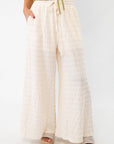 Close-up of cream wide-leg knit pants with a wavy texture, featuring a drawstring waist and relaxed fit for effortless style.