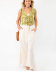 Model wearing wavy textured cream wide-leg knit pants with a green floral vest, styled for a casual summer outfit.