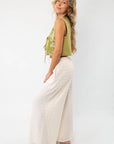 Side view of cream wide-leg knit pants with a wavy texture, highlighting their flowy silhouette and comfortable fit.
