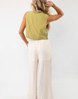 Back view of wavy textured cream wide-leg knit pants, showcasing their elastic waistband and relaxed drape.
