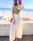 Wavy textured cream wide-leg knit pants styled with a green crop top and sandals, perfect for a beachside summer look.