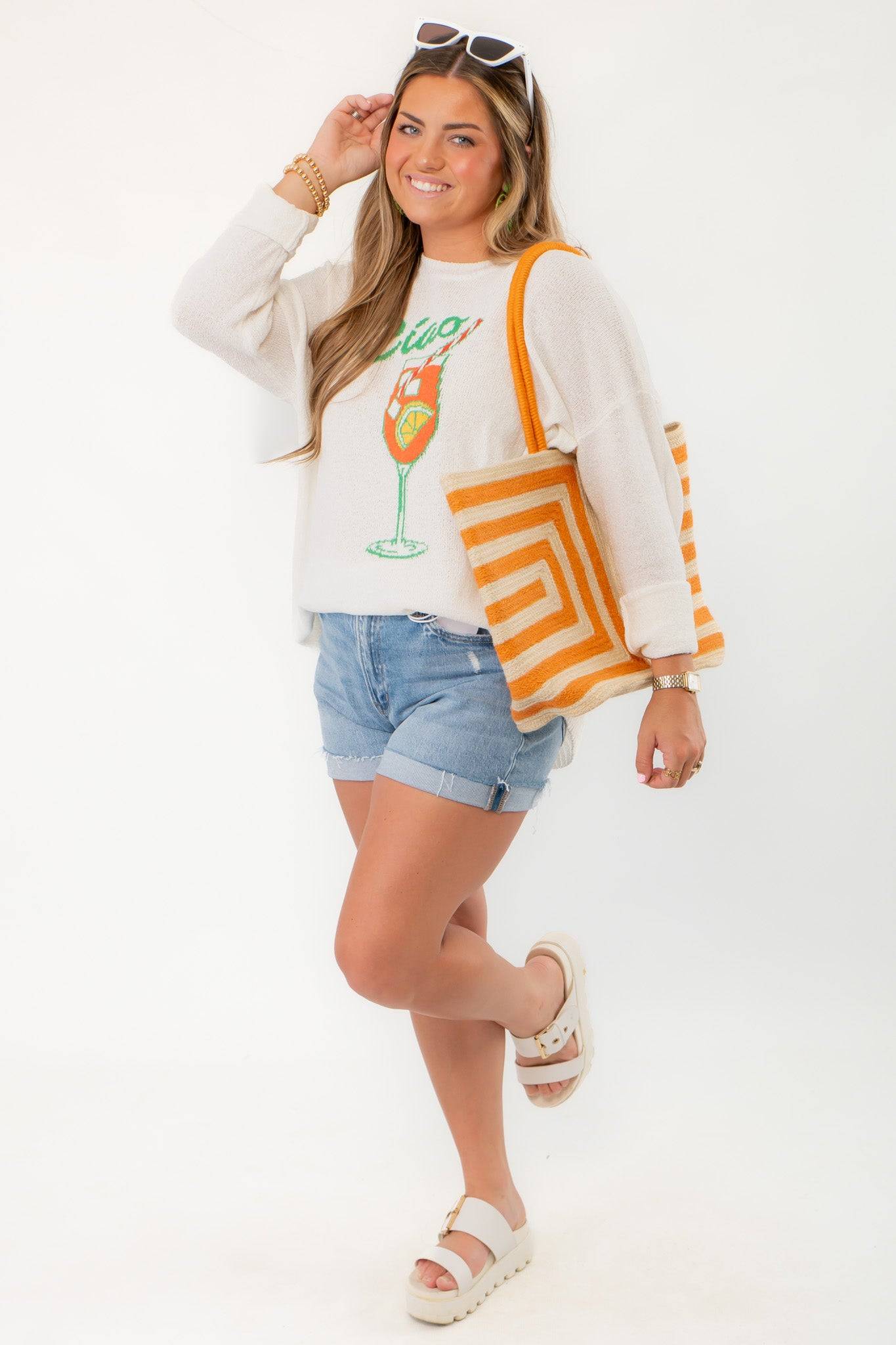 Elevate your style with the Show Me Your Mumu Ciao Cocktail Woodsy Sweater paired with striped orange tote and platform sandals.